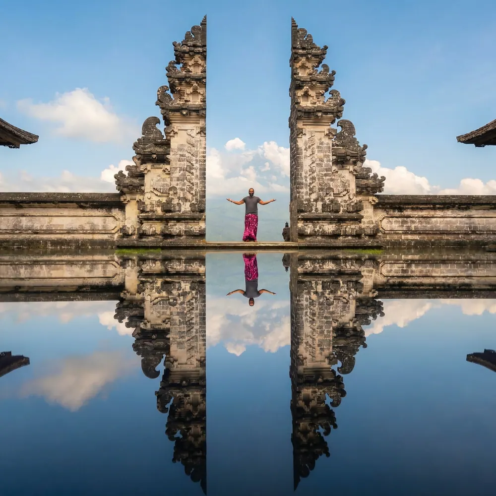 Split stone temple gates reflected in water under a blue sky