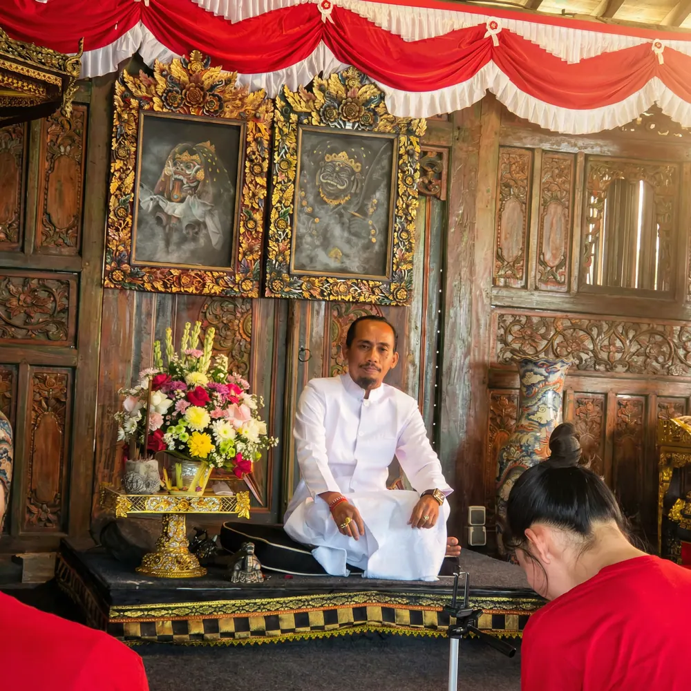 Priest in white leading a ceremony at an ornate carved shrine