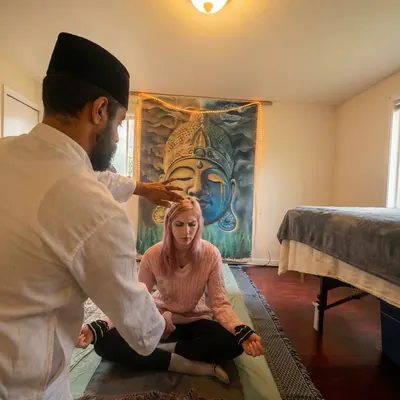 Practitioner resting a hand on the head of a seated woman