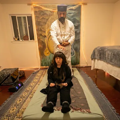 Ali standing behind a woman seated on a mat in the healing room