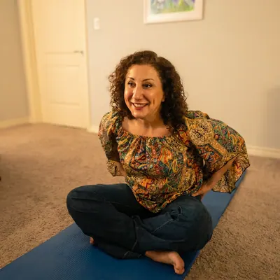 Smiling woman seated on a yoga mat