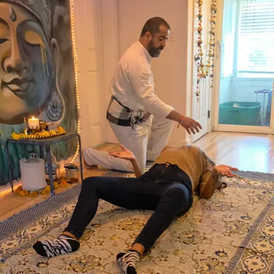 Ali leaning over a client lying on a rug during a session