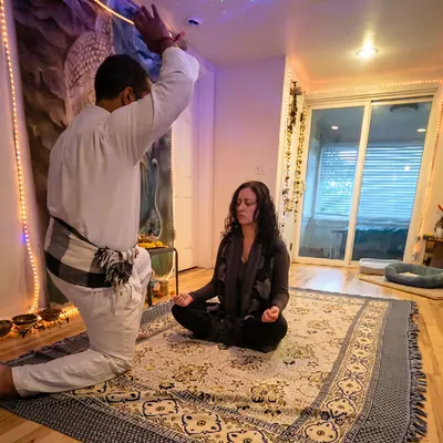 Ali kneeling beside a woman seated in meditation